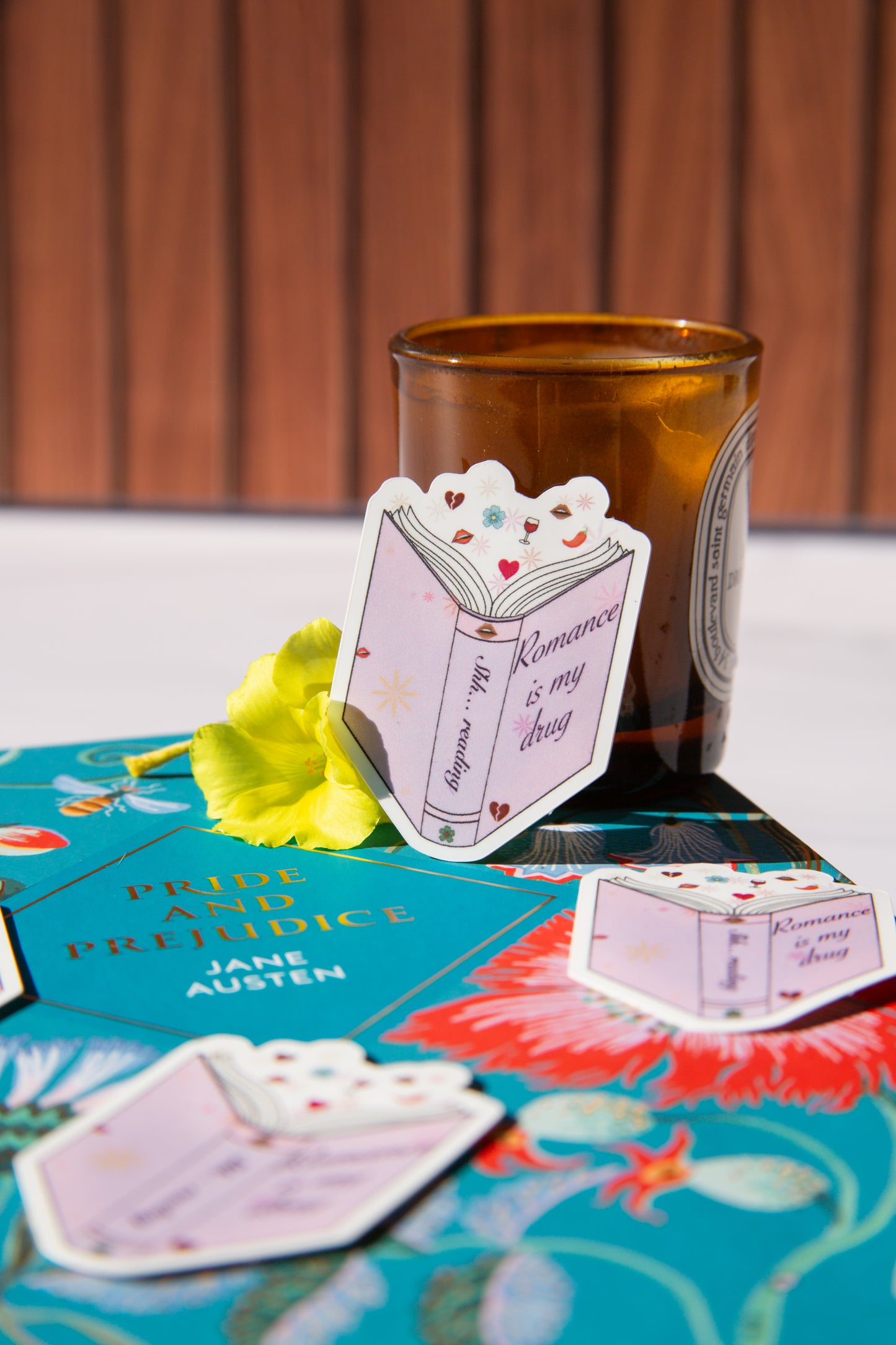 Brown glass with decorative cards on a surface featuring 'Pride and Prejudice' by Jane Austen.