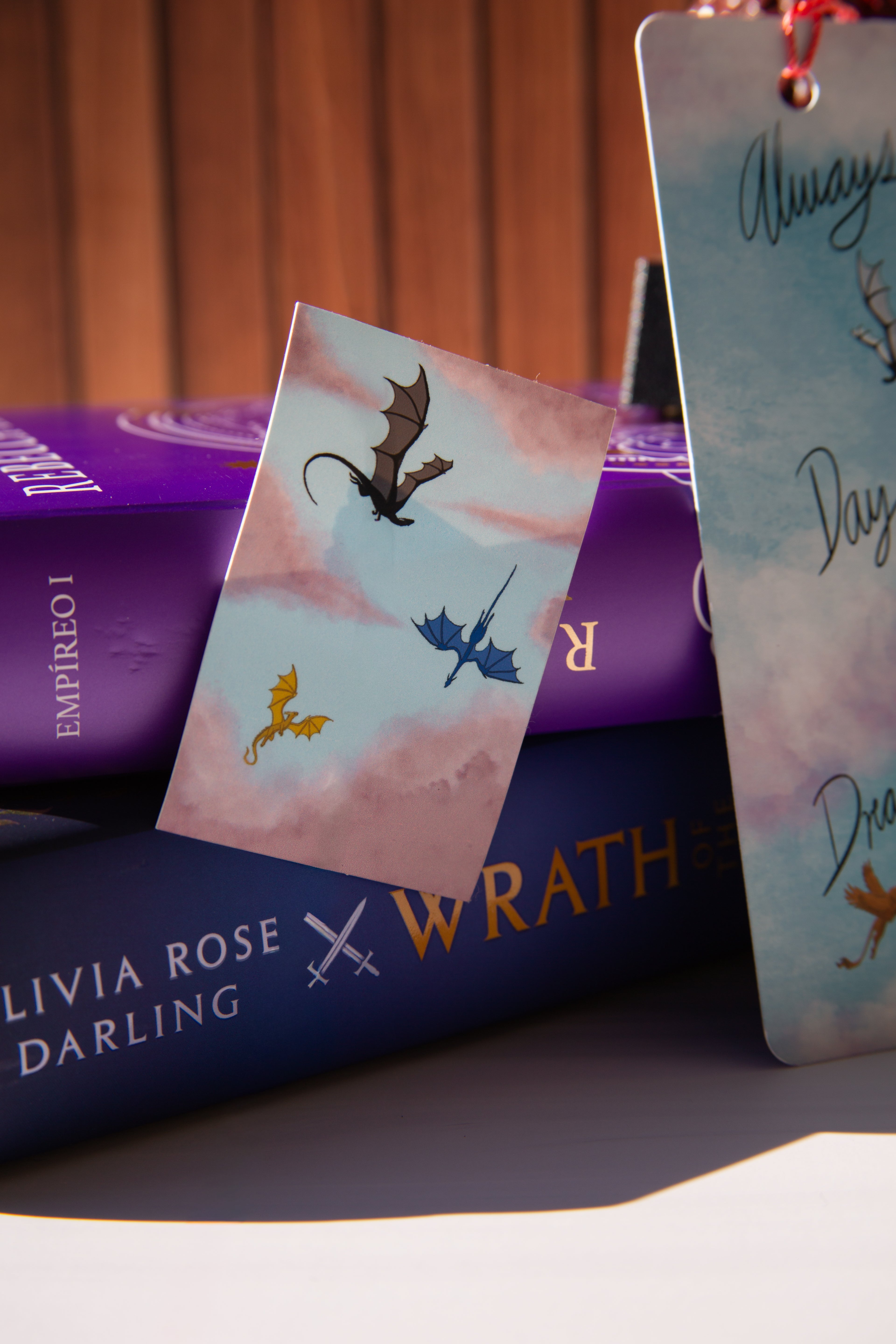 Stack of books with dragon-themed bookmarks on a wooden surface