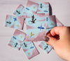 Hand holding a card with dragon illustrations on a pink and blue background